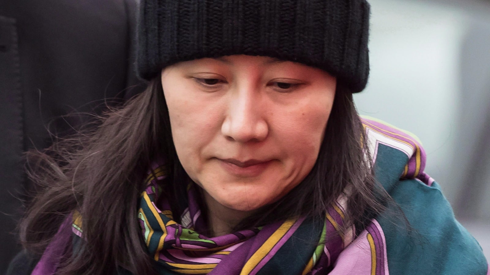 La directrice financière de Huawei, Meng Wanzhou, portant tuque et châle en compagnie d'un agent de sécurité à Vancouver, le 12 décembre 2018.