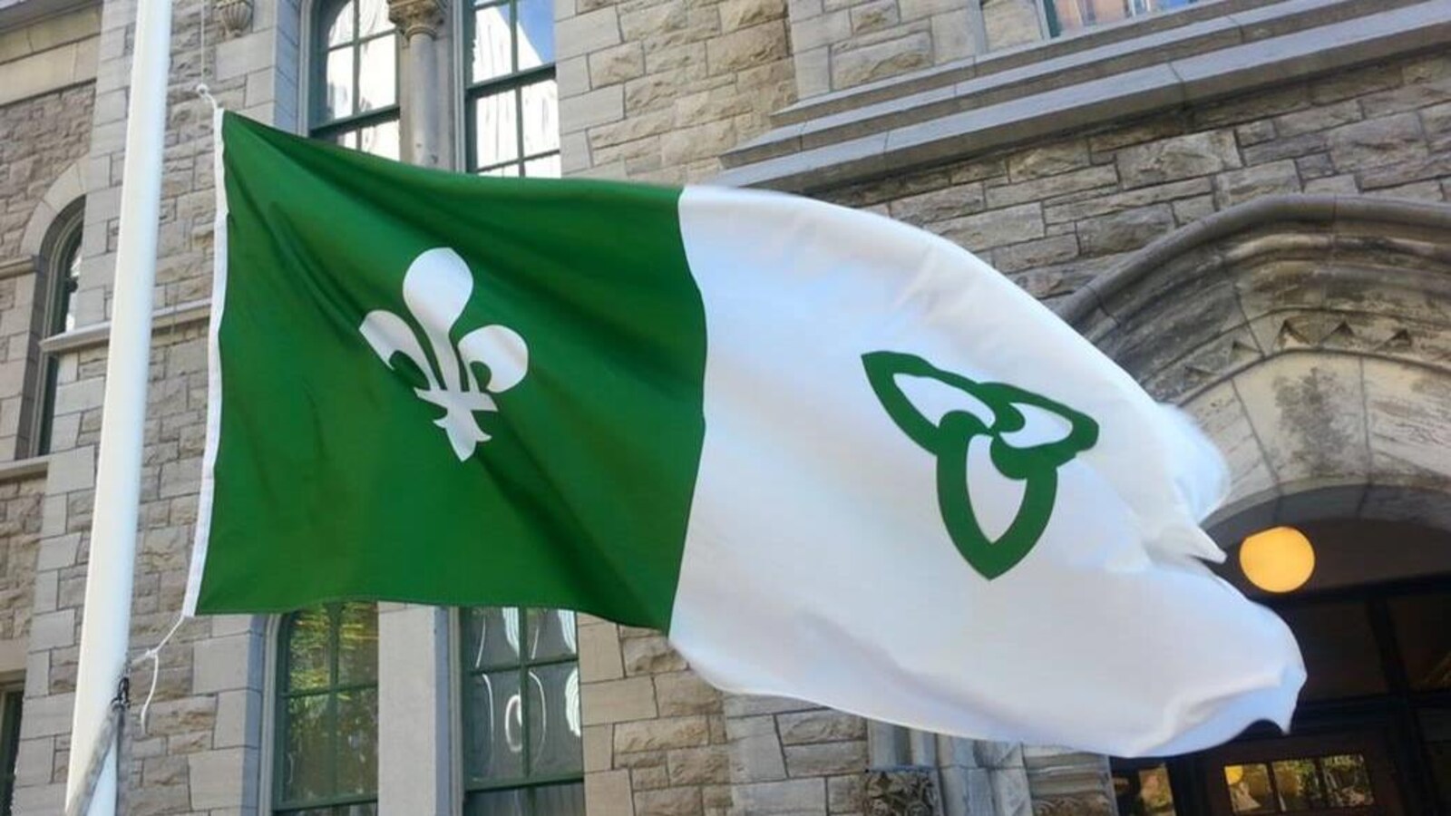 Un drapeau vert et blanc flotte au vent.