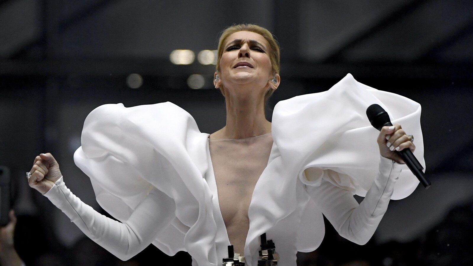 La chanteuse Céline Dion, microphone en main et vêtue d'une robe blanche, donne une prestation sur une scène lors de la soirée de remise des prix Billboard, à Las Vegas, en mai 2017.