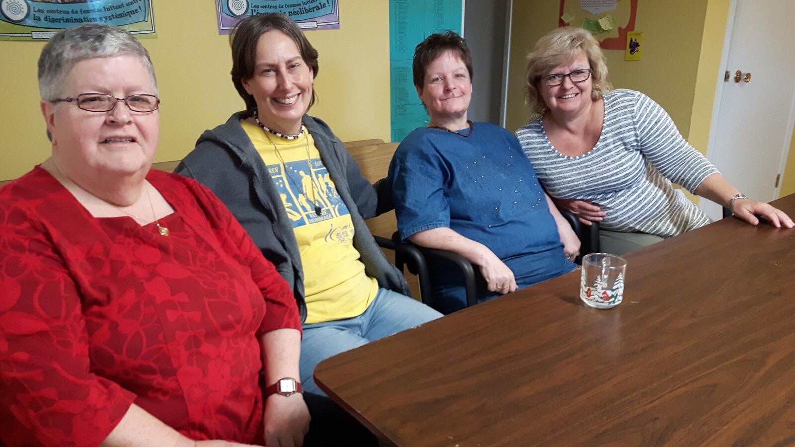Quatre femmes sourient à la caméra, assises derrière une table.