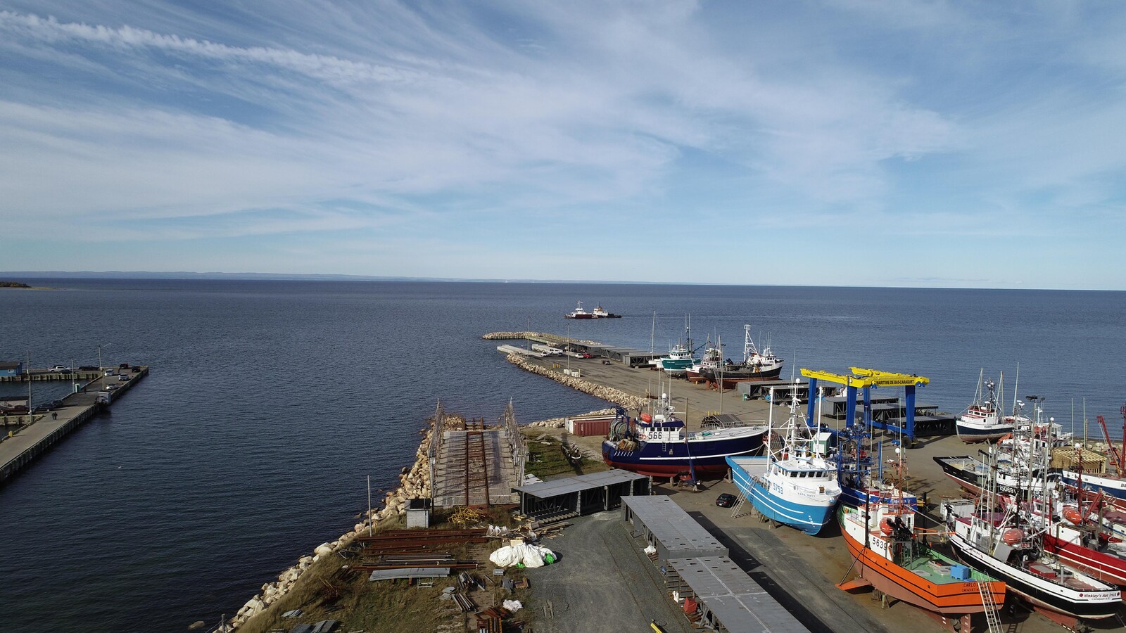Vue aérienne du chantier naval montrant les quais et quelques bateaux stationnés sur la terre ferme.