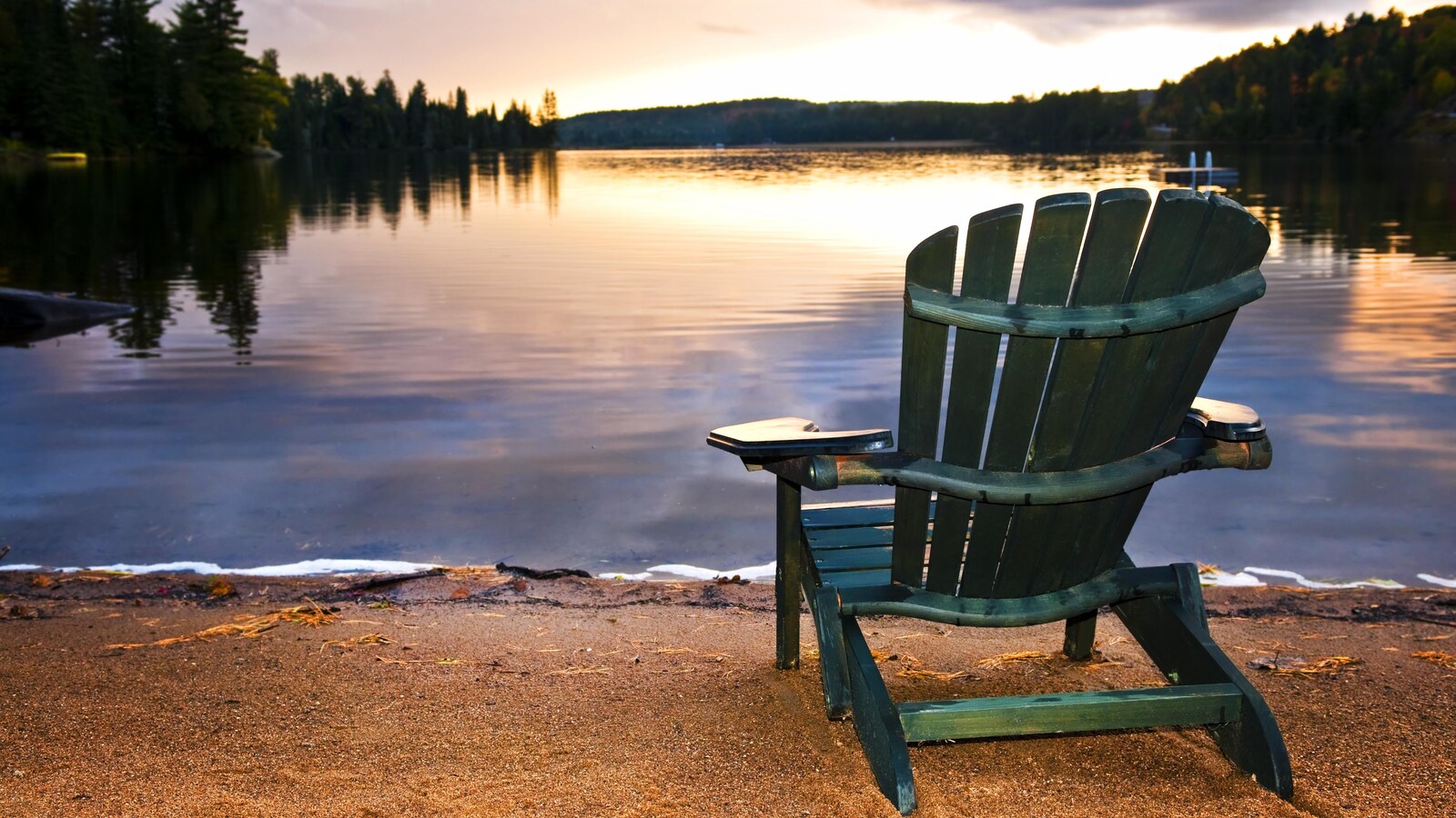 Une chaise installée sur le bord d'un lac au coucher de soleil.