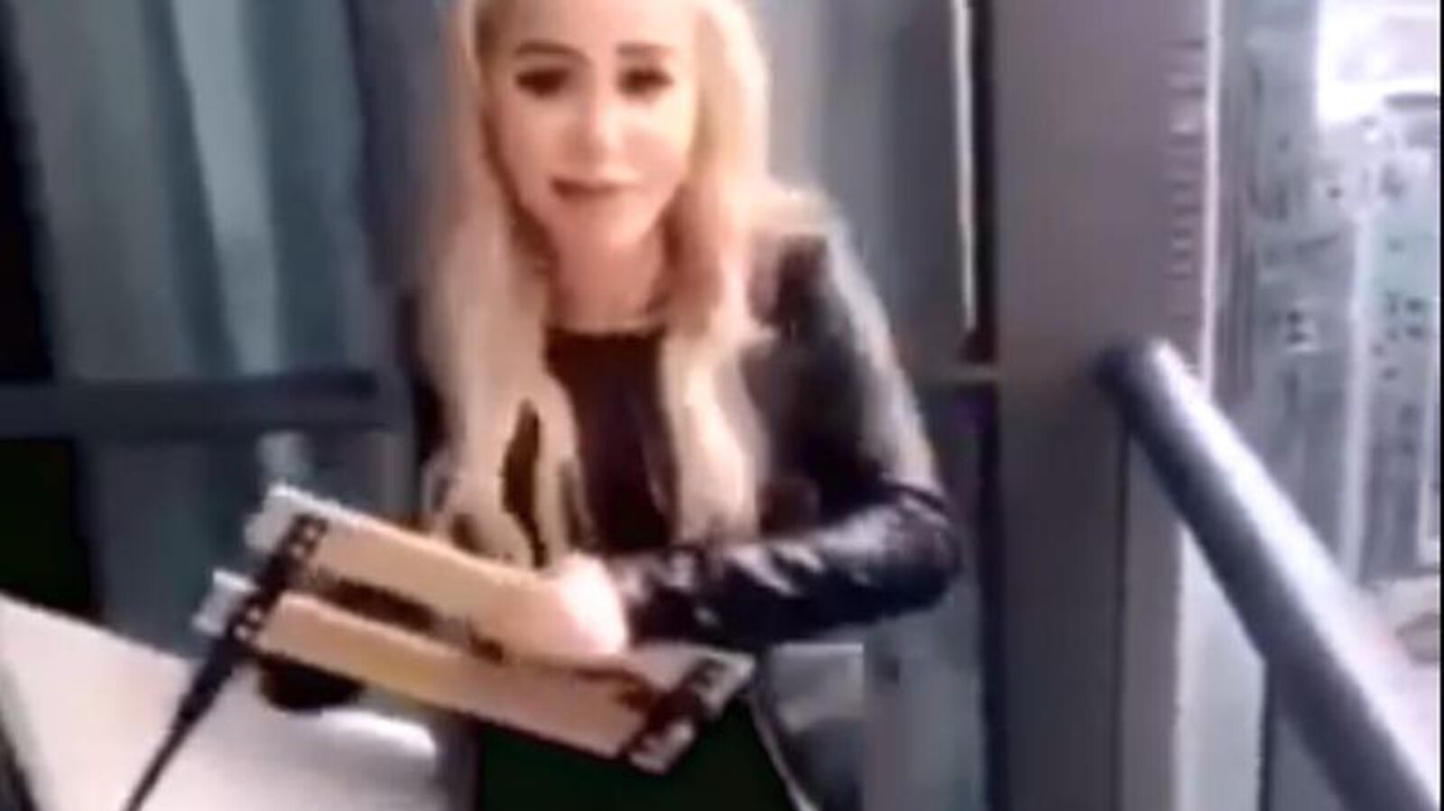 Photo d'une femme aux cheveux blonds qui tient une chaise pliante dans les mains.