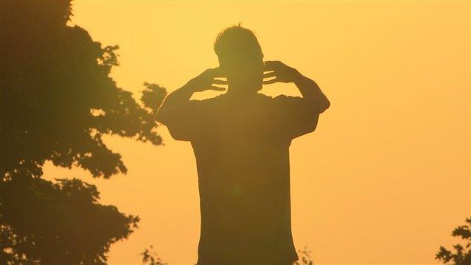 Un homme debout face au soleil.