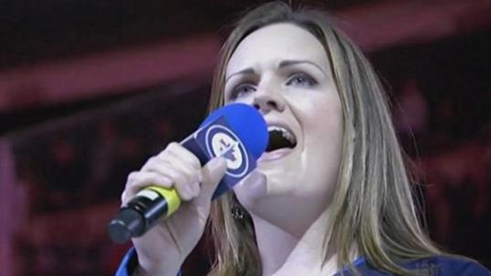 Une femme chante dans une micro.