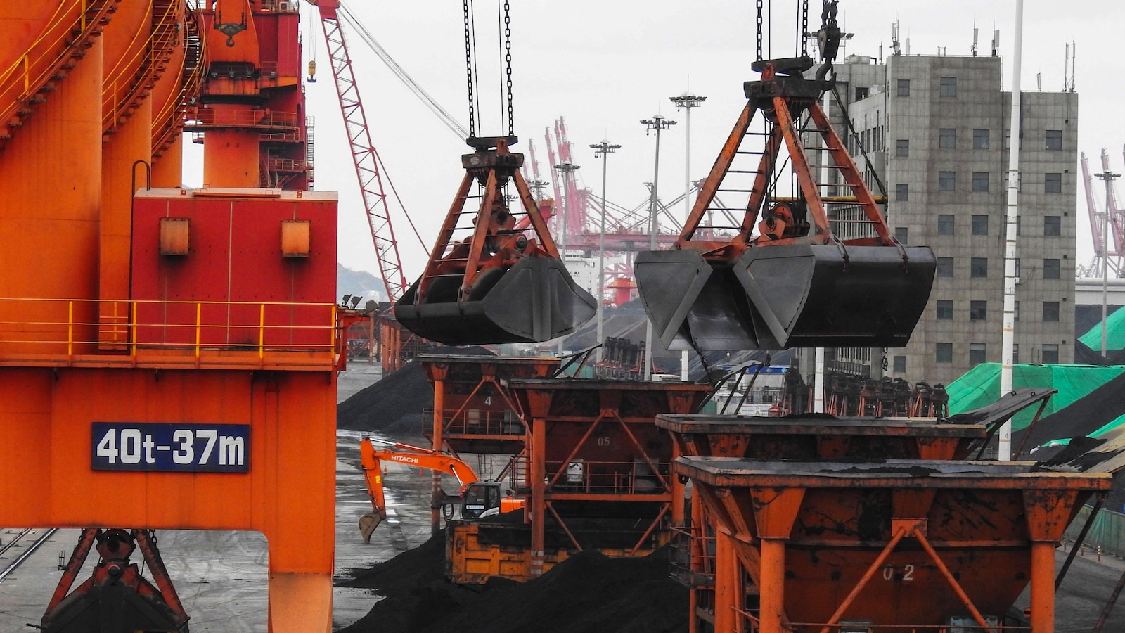 Des grues transfèrent des quantités de charbon dans des conteneurs dans un port chinois.