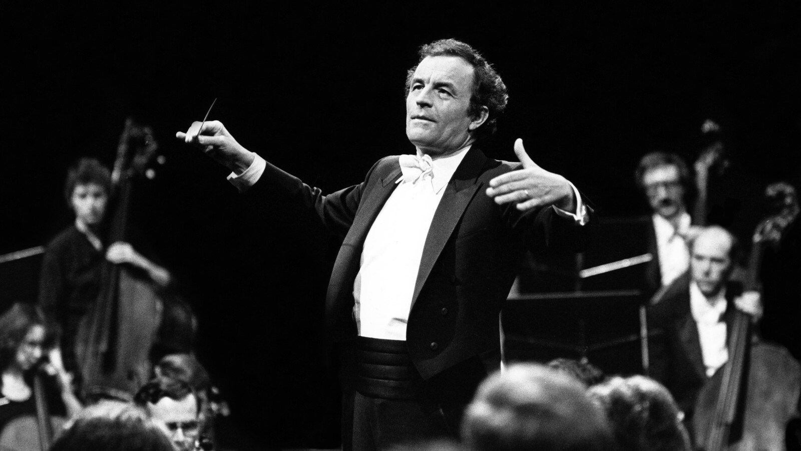 Entouré des musiciens, Charles Dutoit lève les bras et agite sa baguette.