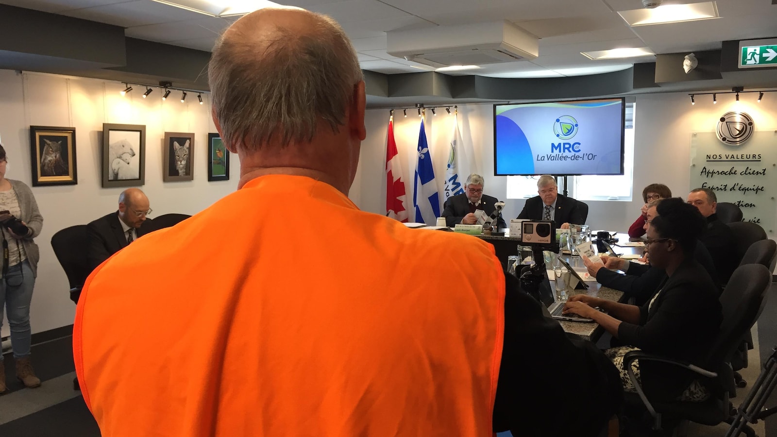 Un chasseur portant une veste fluorescente parle devant un conseil des maires.