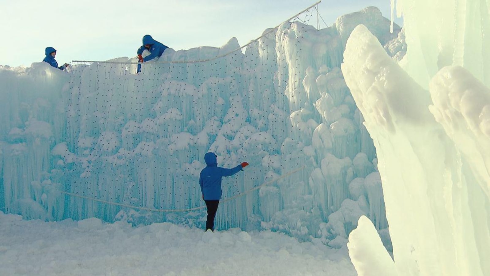 Trois artisans sculptent un mur de glace, en plein hiver.