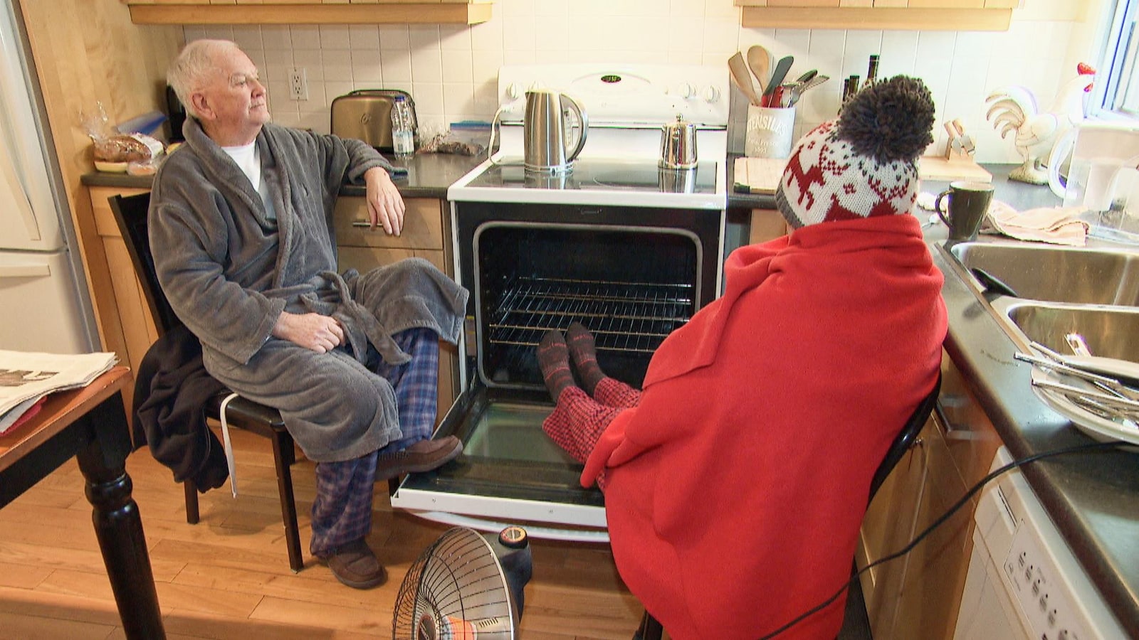 Un homme et une femme âgés, habillés chaudement, dans une cuisine.