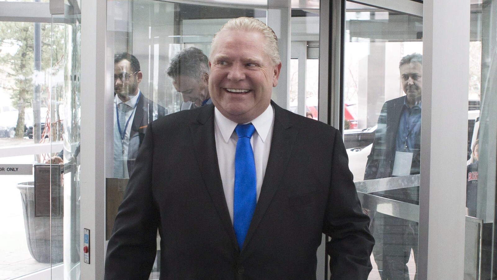 Doug Ford sourit, portant un complet et une cravate bleue.