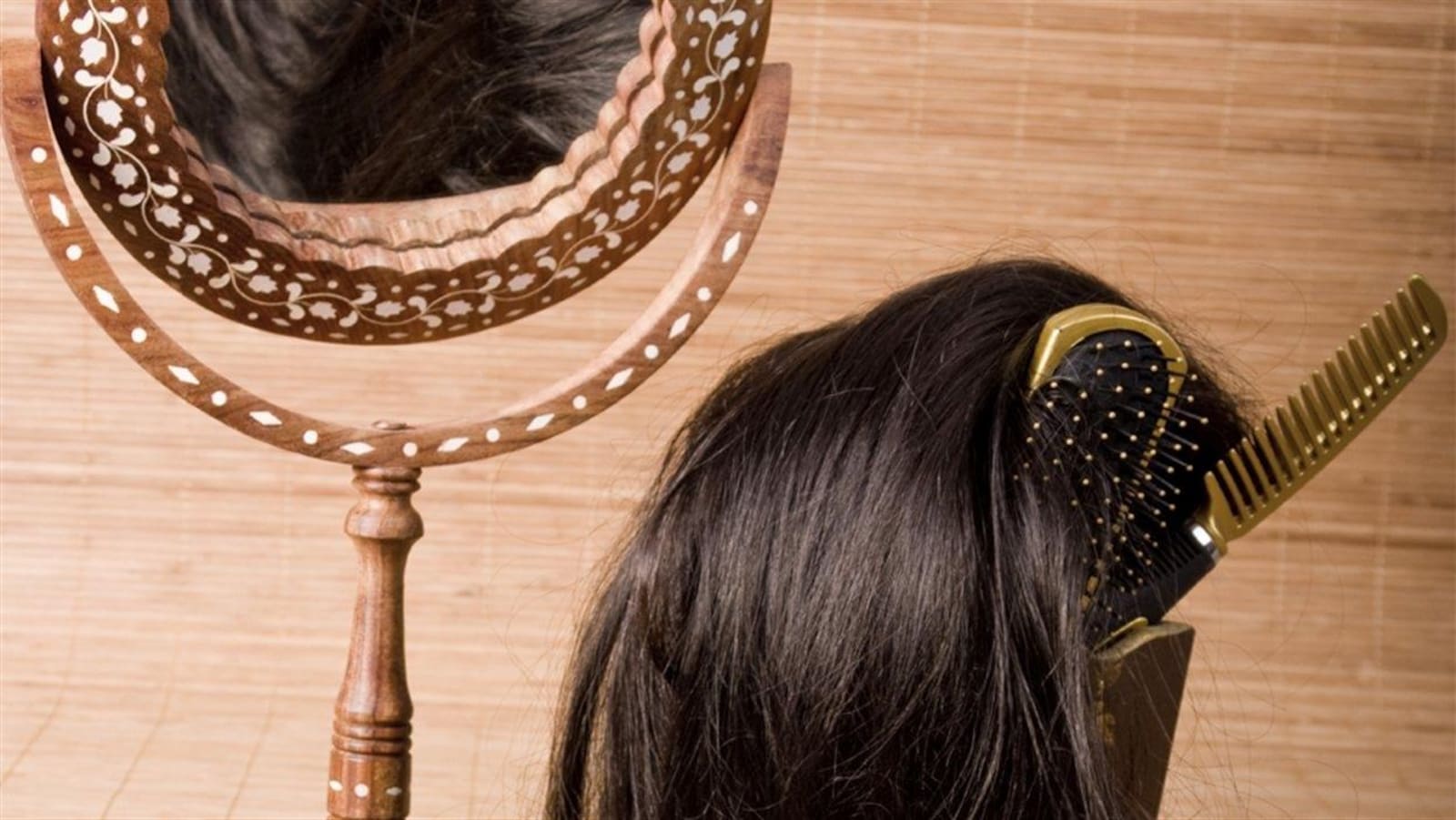 Une perruque de cheveux bruns repose aux côtés de brosses et d'un miroir.