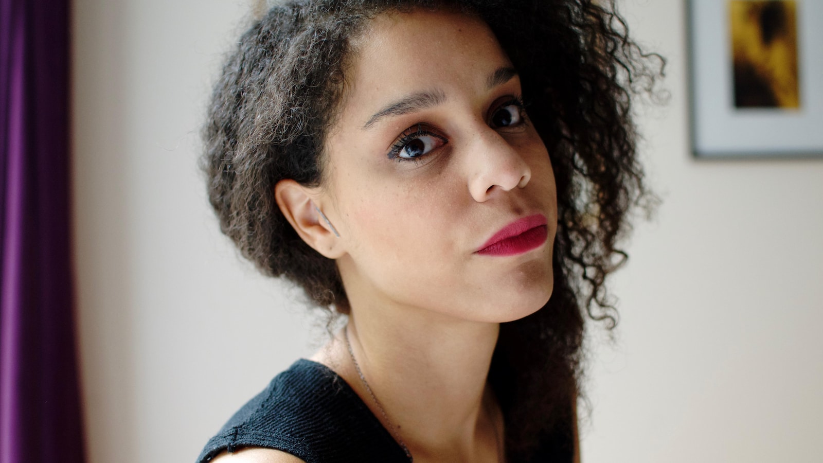 Portrait de l'auteure Chloé Savoie-Bernard, de trois-quart, la tête légèrement penchée en arrière, avec du rouge à lèvres.