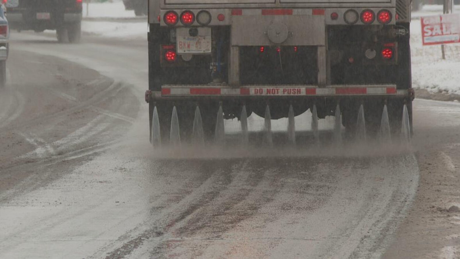 Un camion déverse un mélange liquide à base de chlorure de calcium sur une route.