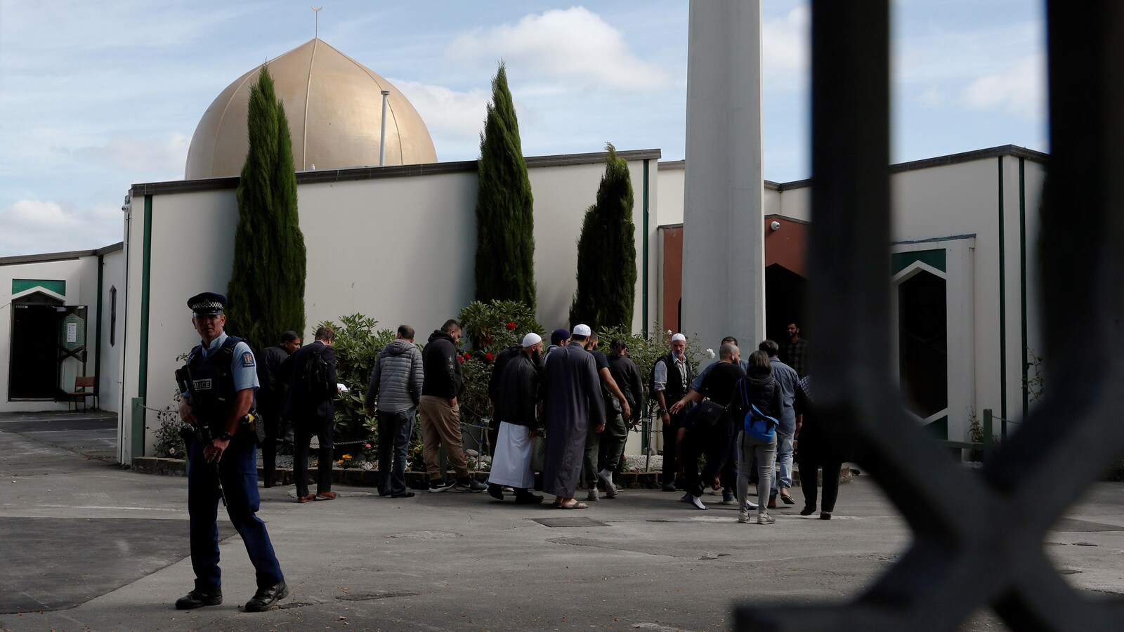 Un policier armé devant quelques fidèles à l'extérieur d'une mosquée