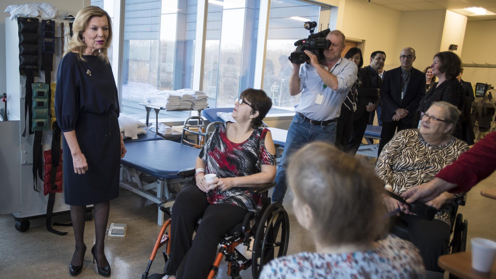 Une femme parle à des dames en fauteuil roulant alors qu'un caméraman tourne.