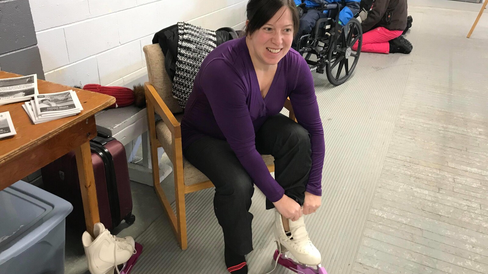 Christine Moore sourit en enfilant ses patins à glace.