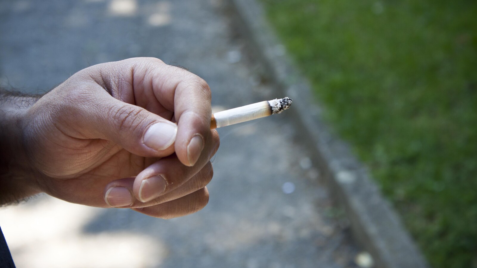 Une main tenant une cigarette allumée.