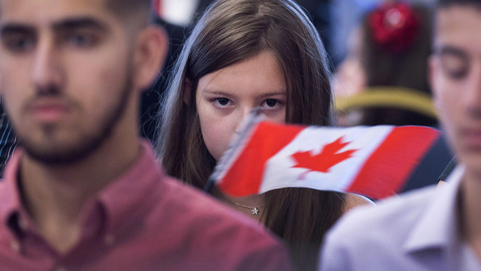 Une jeune fille tient un drapeau canadien.