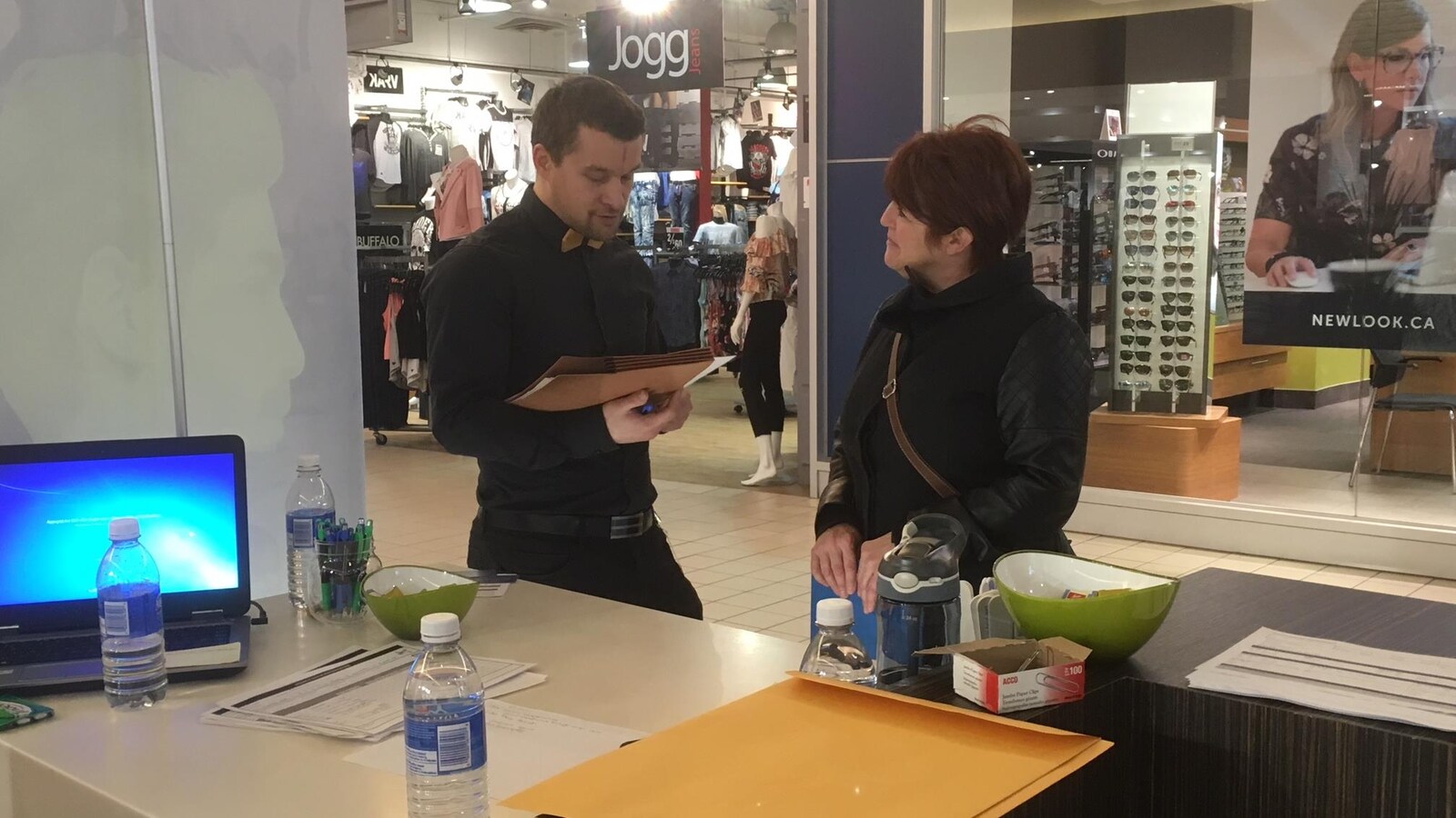 Un homme étudie les informations d'une dame venue porter son dossier.