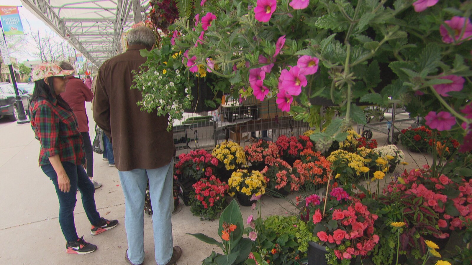 Des passant regardent des fleurs dans une pépinière.