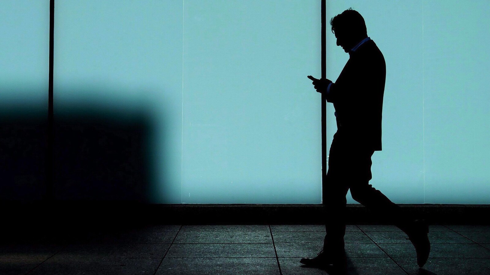 Une photo d'un homme qui marche en regardant son téléphone portable.