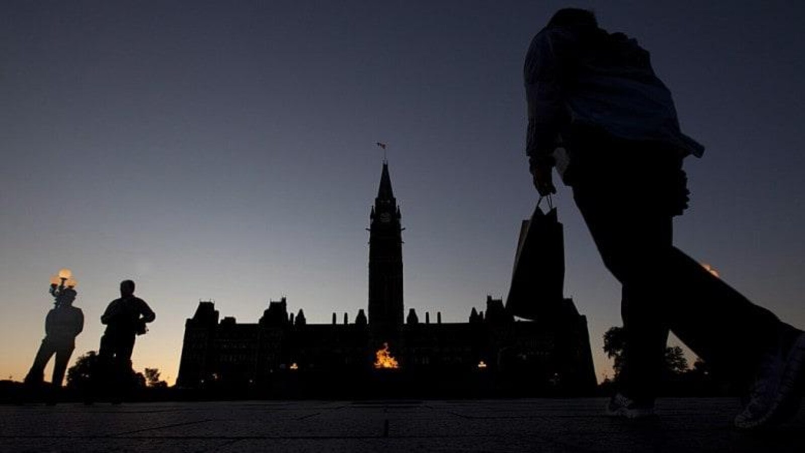 Des personnes devant la colline du Parlement de nuit.