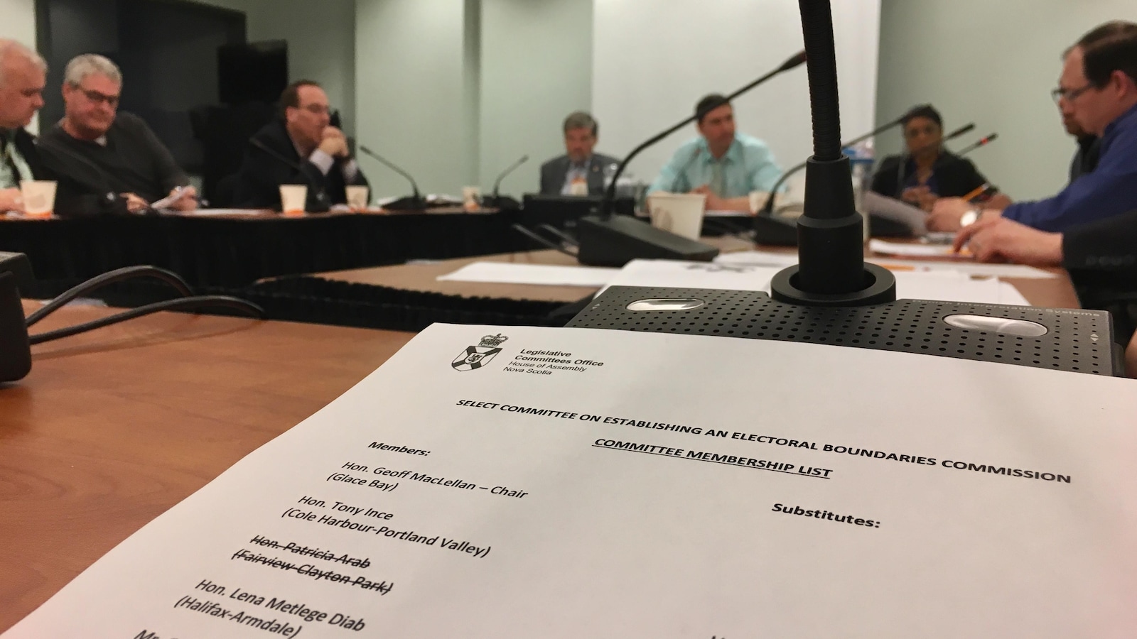 Gros plan sur un document du comité et membres du comité assis autour d'une table.