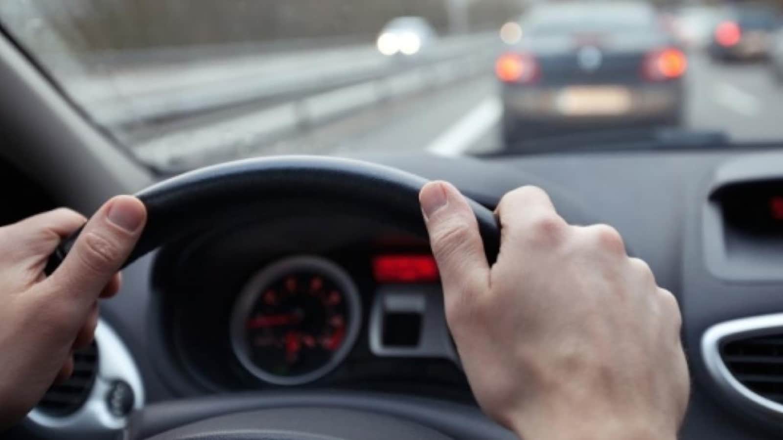 Des mains sur un volant dans une voiture.
