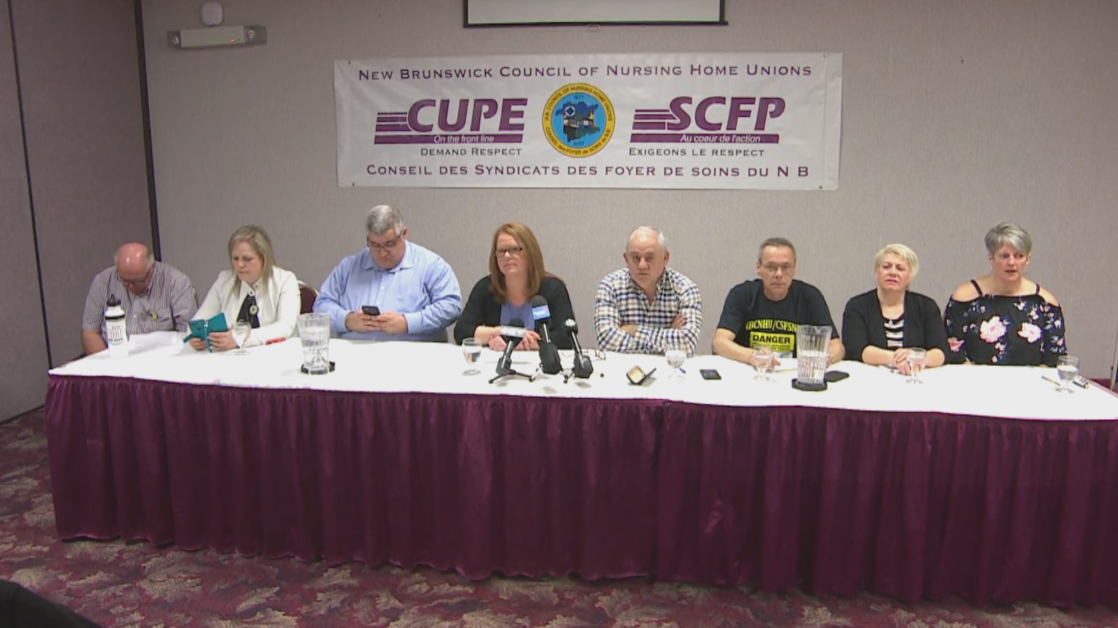 Huit représentants assis à une table donnent une conférence de presse