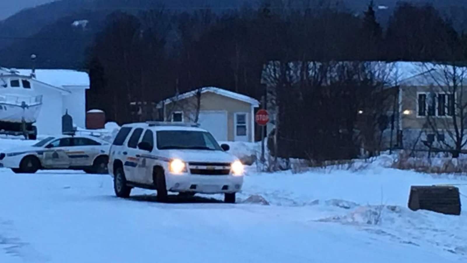 Deux voitures de police garées devant une maison au crépuscule.