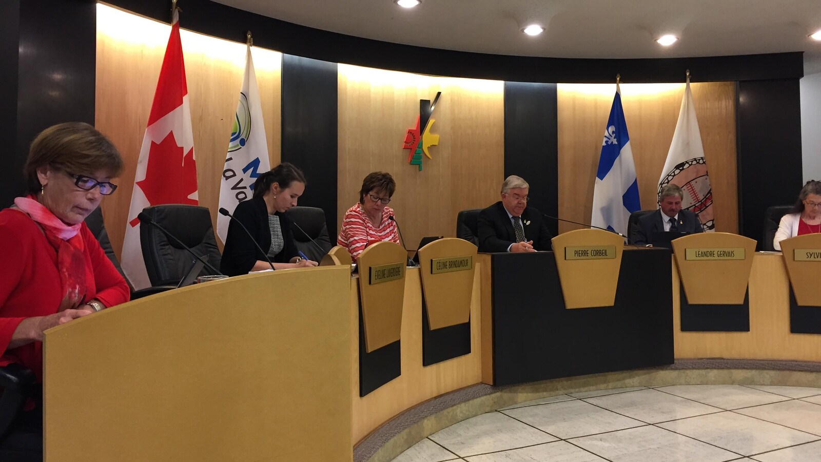 Des élus sont assis derrière leur bureau lors de la séance d'un conseil municipal.