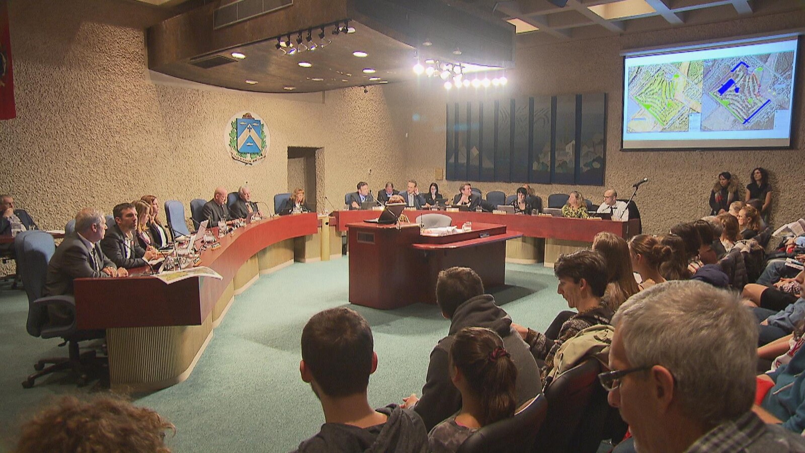 Des cartes comparatives du projet immobilier sont présentées aux citoyens présents dans la salle du conseil à Trois-Rivières.