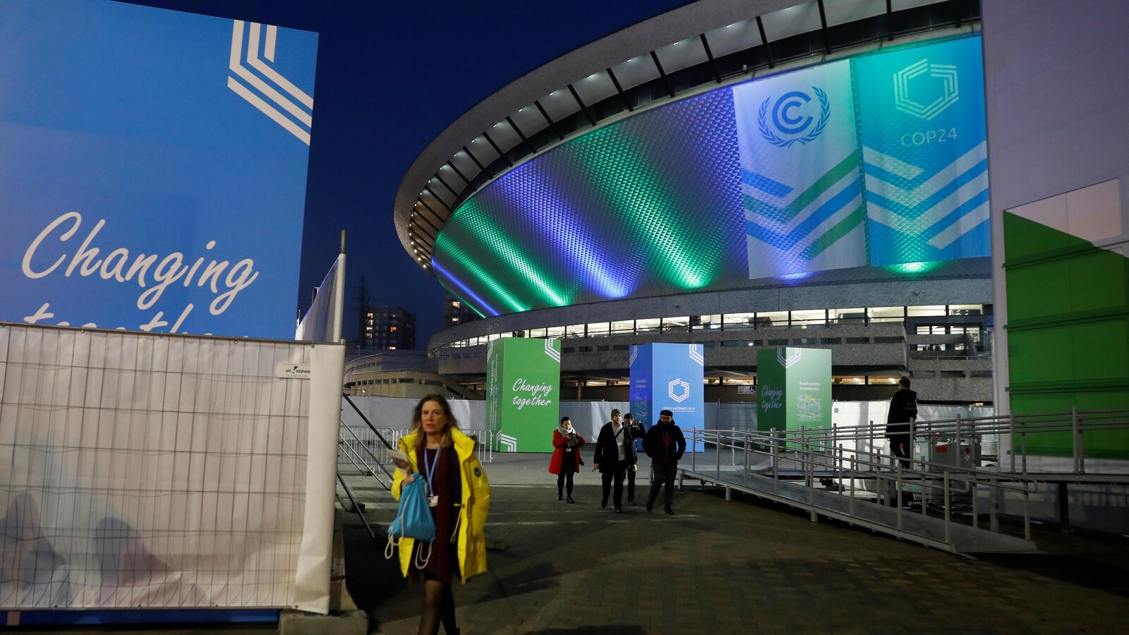 Des personnes marchent devant un stade où se déroule la COP24 en Pologne.