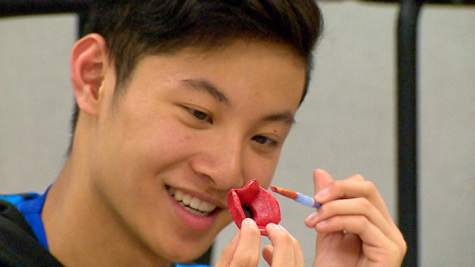 Un jeune homme aux traits asiatiques peint une fleur de terre cuite.