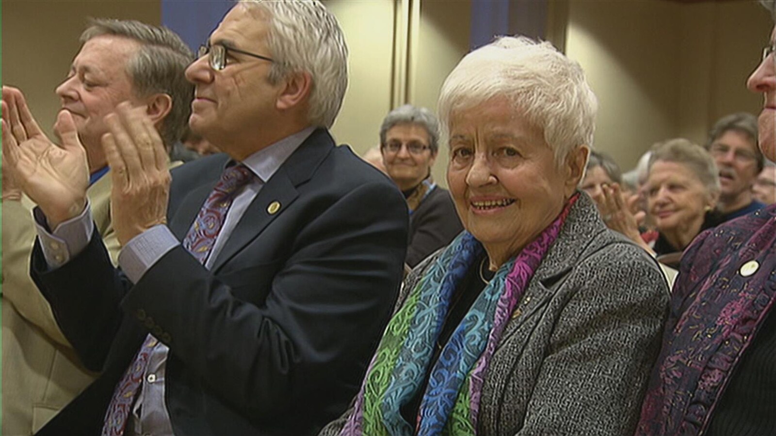 La dame dans une assemblée regarde la caméra.