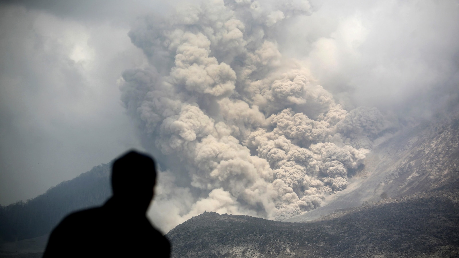 Un homme, de dos, observe une coulée pyroclastique.