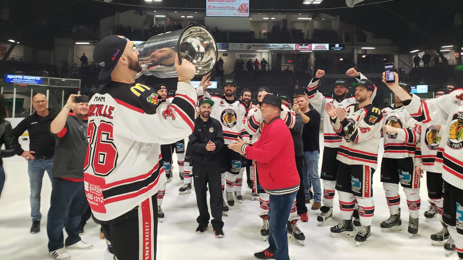Des joueurs célèbrent leur victoire au hockey en soulevant une coupe.