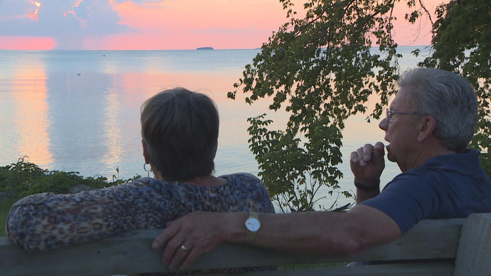 Un homme enlace une femme sur un bas en regardant un bord d'eau.