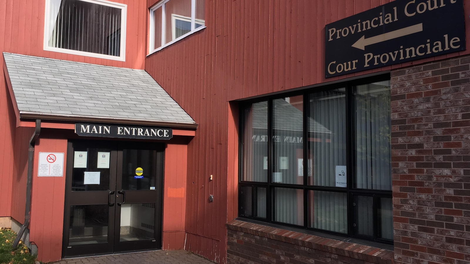 Une porte d'entrée d'un édifice avec une affiche identifiant la Cour provinciale