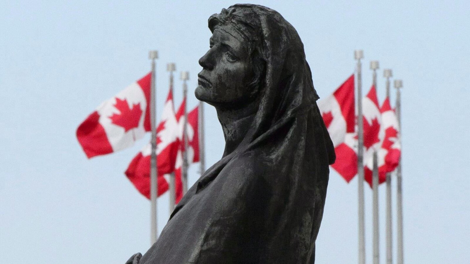 Visage de la statue Veritas entourée de drapeaux du Canada en mai 2018 à Ottawa.