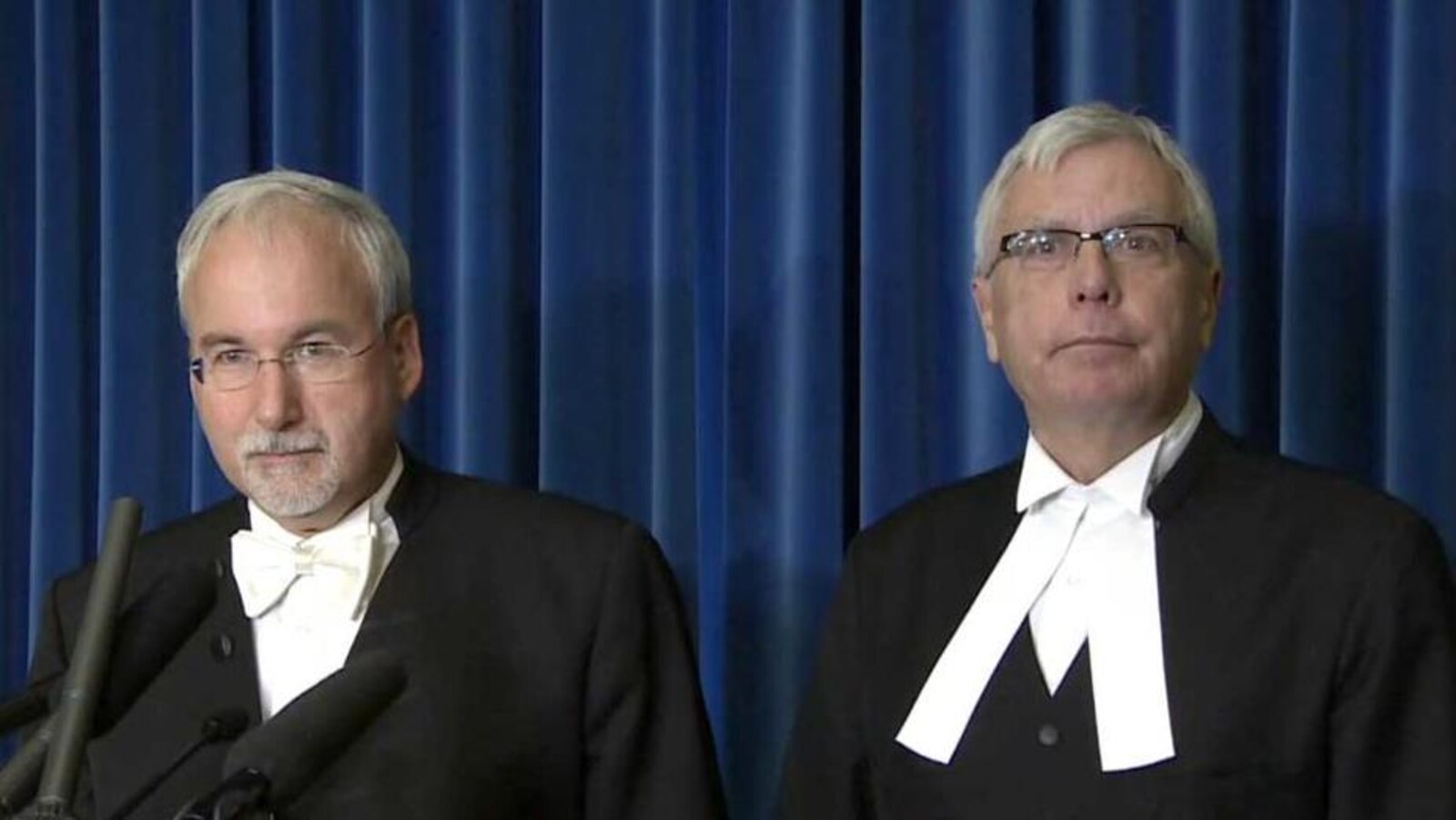 Deux hommes aux cheveux blancs assis côte à côte.
