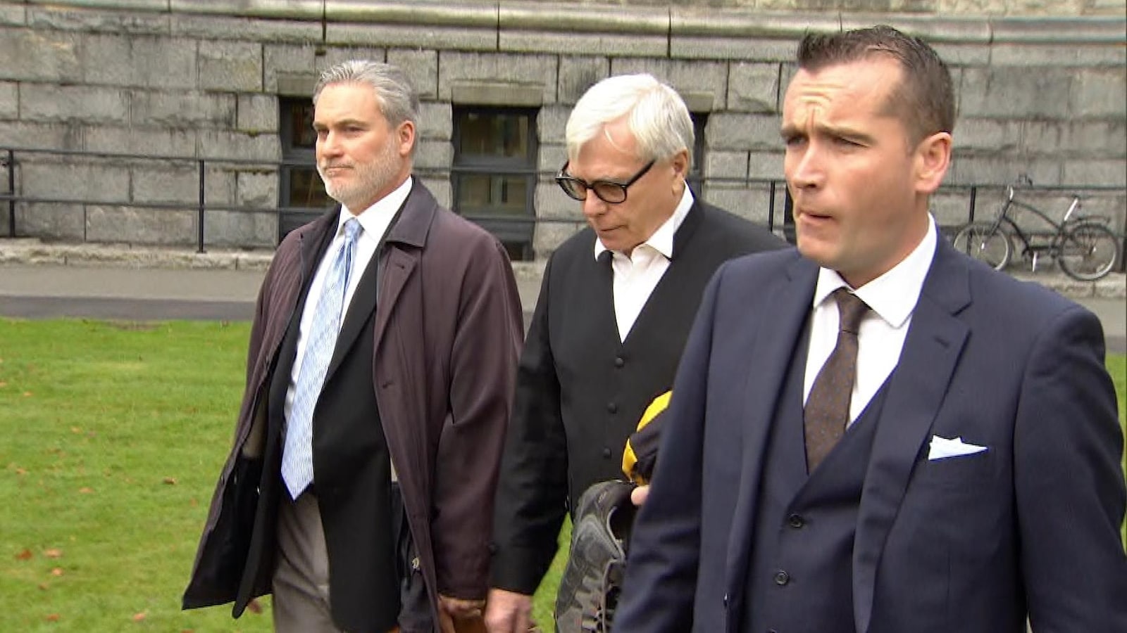 Trois hommes marchent côte à côte.