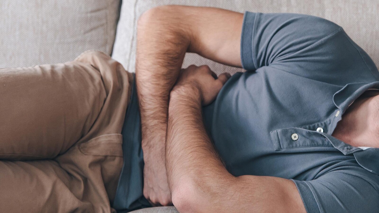 Un homme couché se tient le ventre et semble avoir mal.