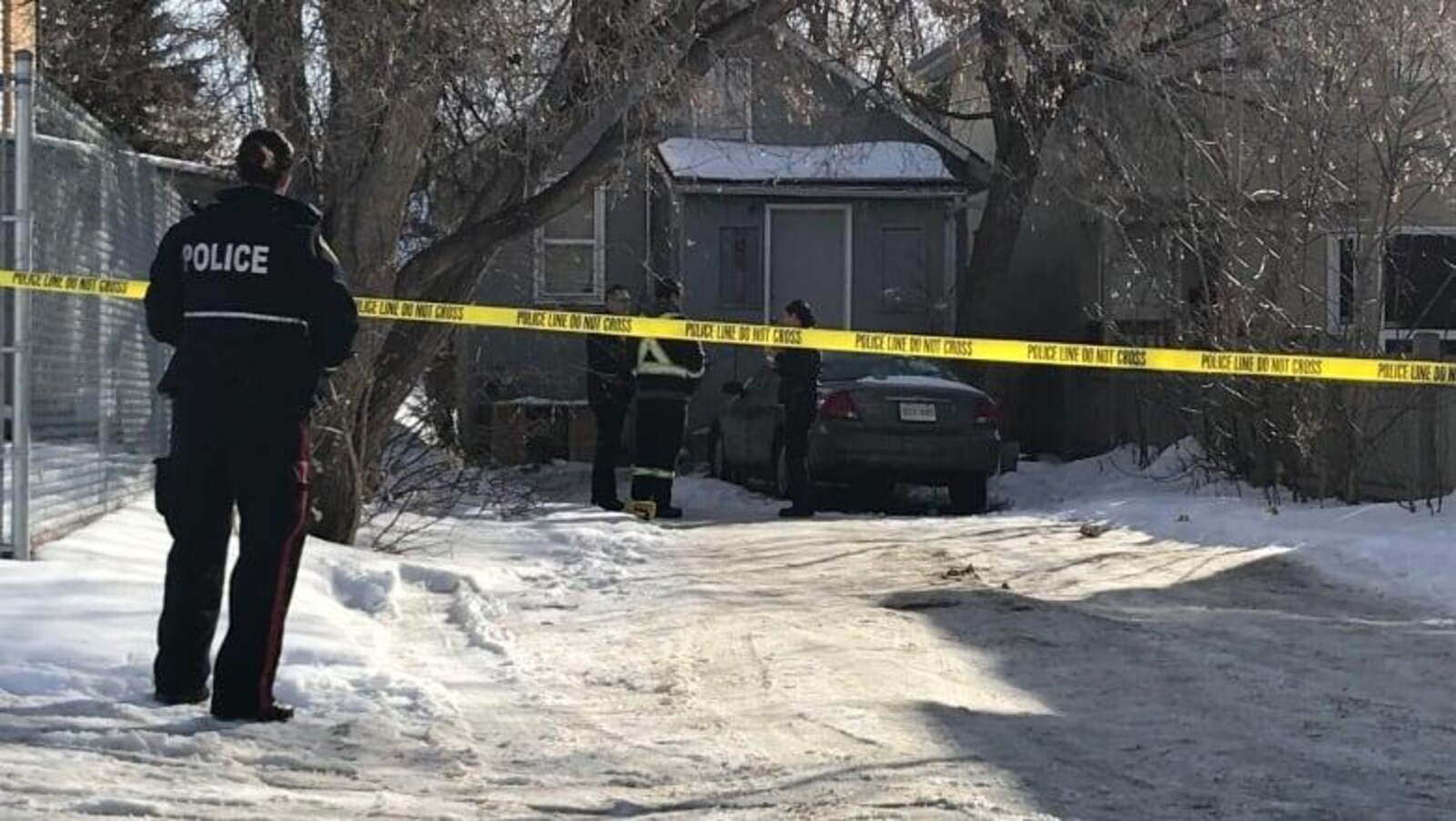 Des policiers discutent en avant d’une maison. Un ruban adhésif jaune interdit l’accès à cette maison.