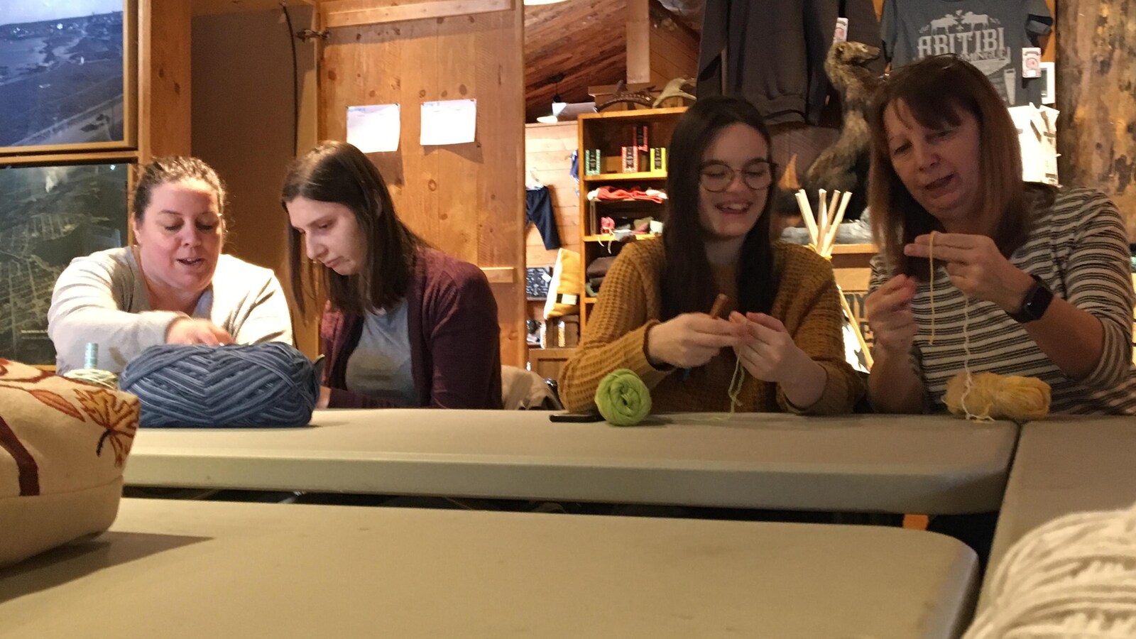 Quatre femmes tiennent un crochet et de la laine en souriant.