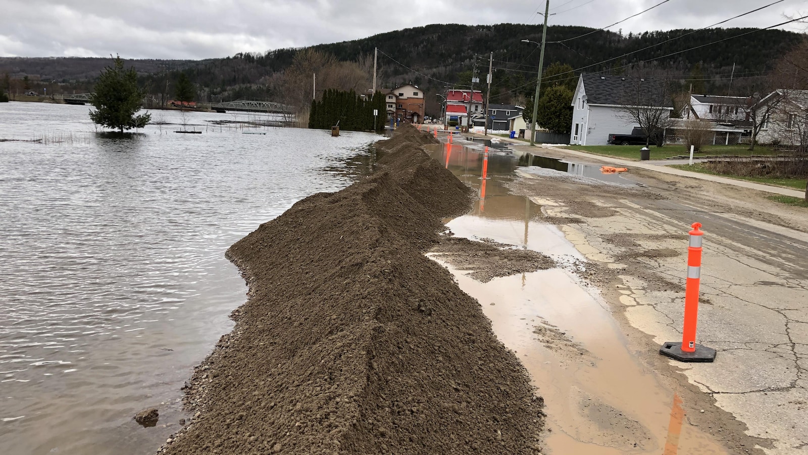 De la terre empilée pour bloquer de l'eau près d'une route.