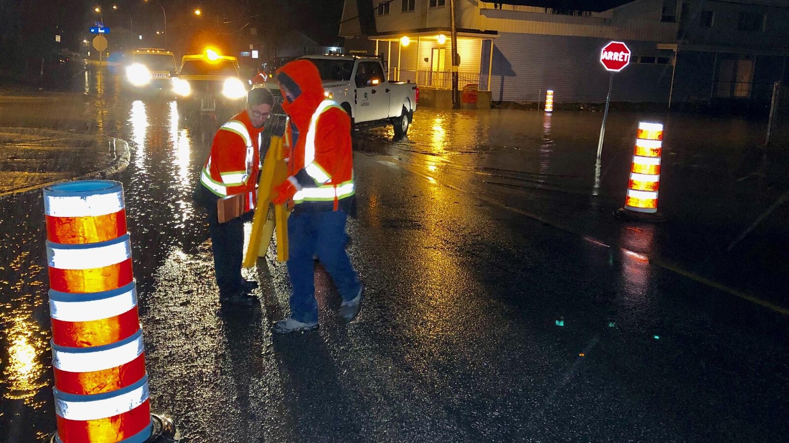 Deux personnes posent des barricades dans un secteur où l'eau monte.