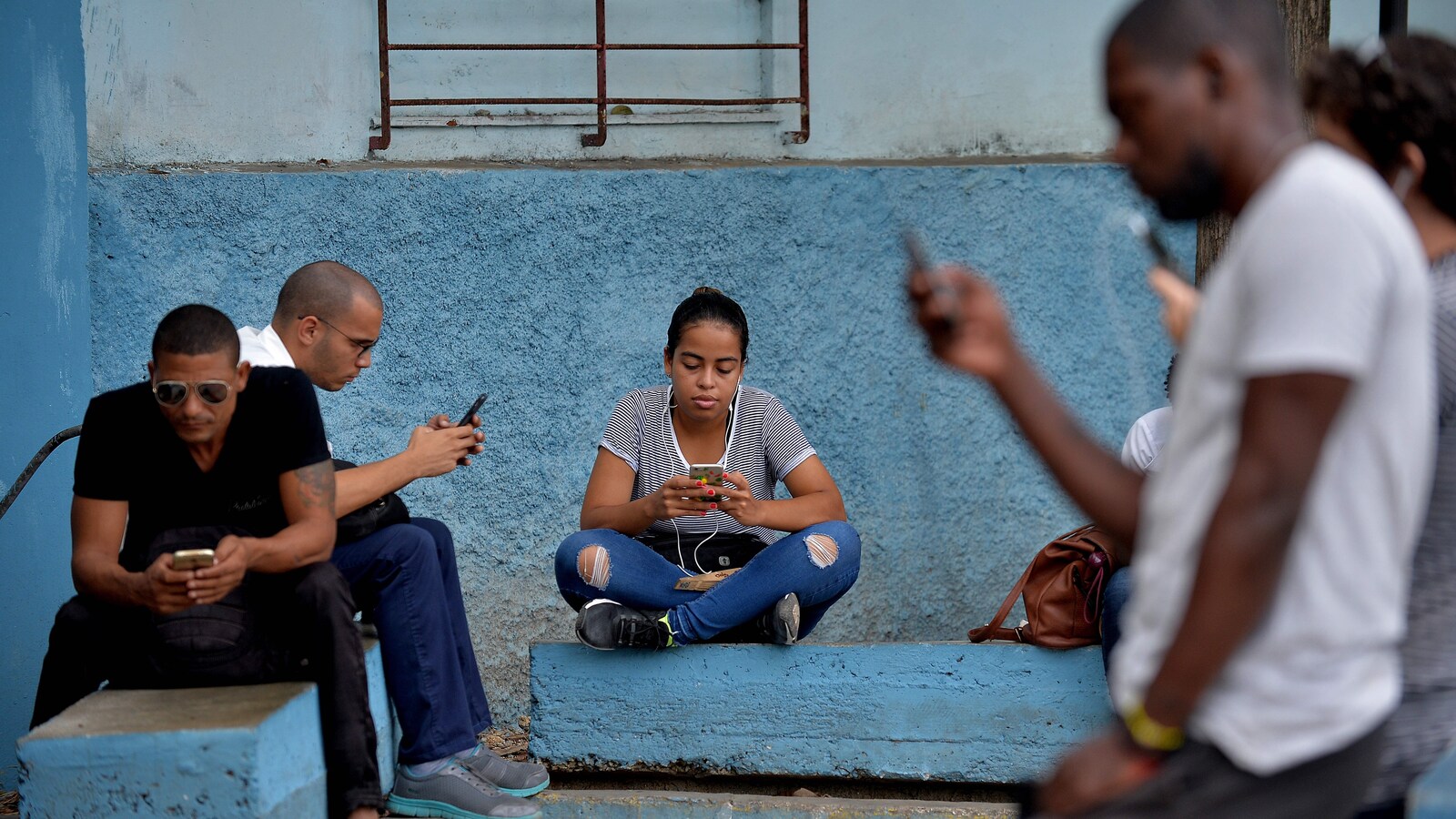 Des personnes consultent leur téléphone mobile dans une rue de Cuba.