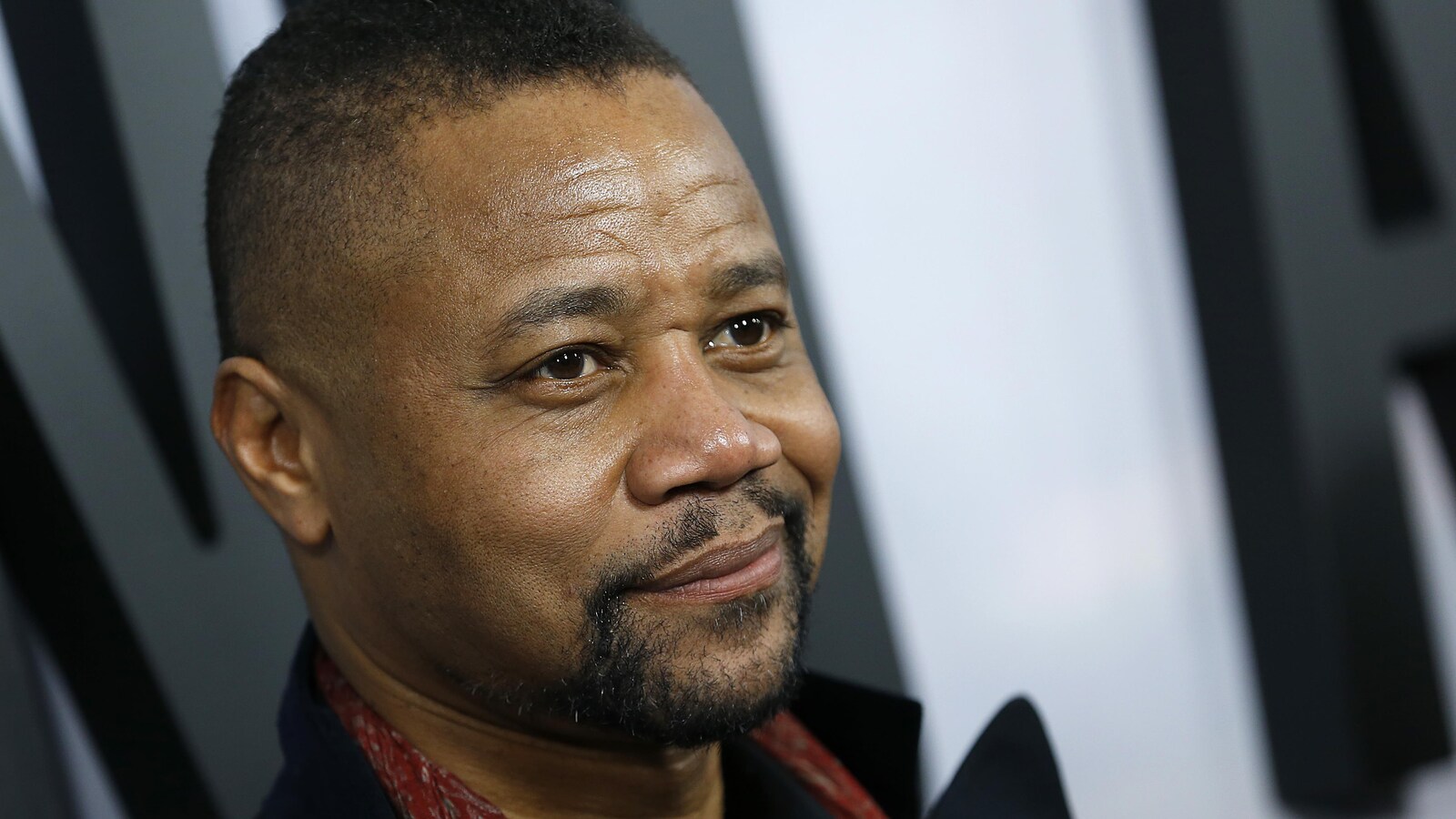 L'acteur Cuba Gooding Jr., portant un manteau noir et posant pour les caméras lors d'une première de film.